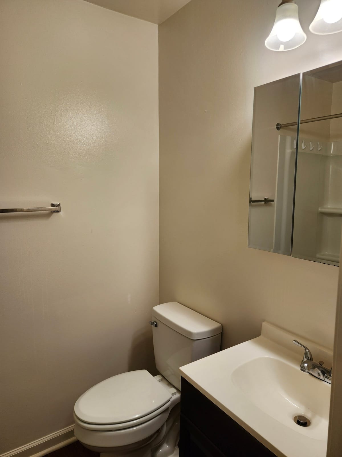 A bathroom vanity at Calvertowne with a sink, a mirrored medicine cabinet, a vanity light, and a toilet beside it