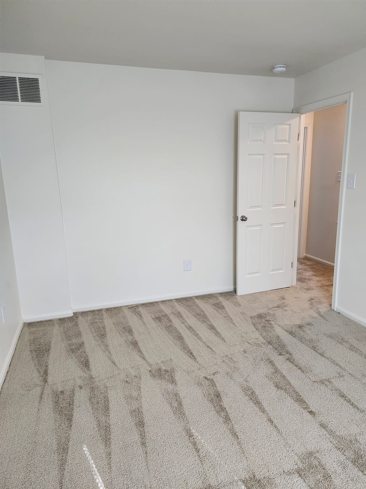 A second carpeted bedroom at Calvertowne with a six-panel door standing open to the hallway